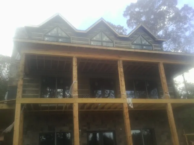 Dormers and porch framing on a large log home under construction — Roof Coating work by our crew in Stow