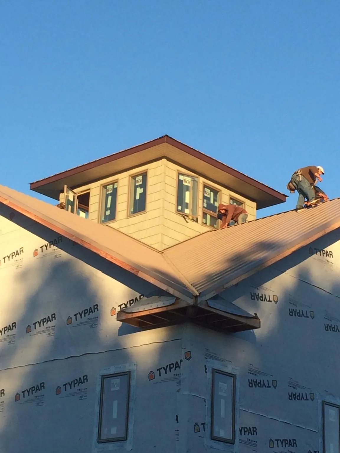 Roofers working around a rooftop cupola on a new metal roof at sunset — Roof Waterproofing in Stow by Roofing Brothers